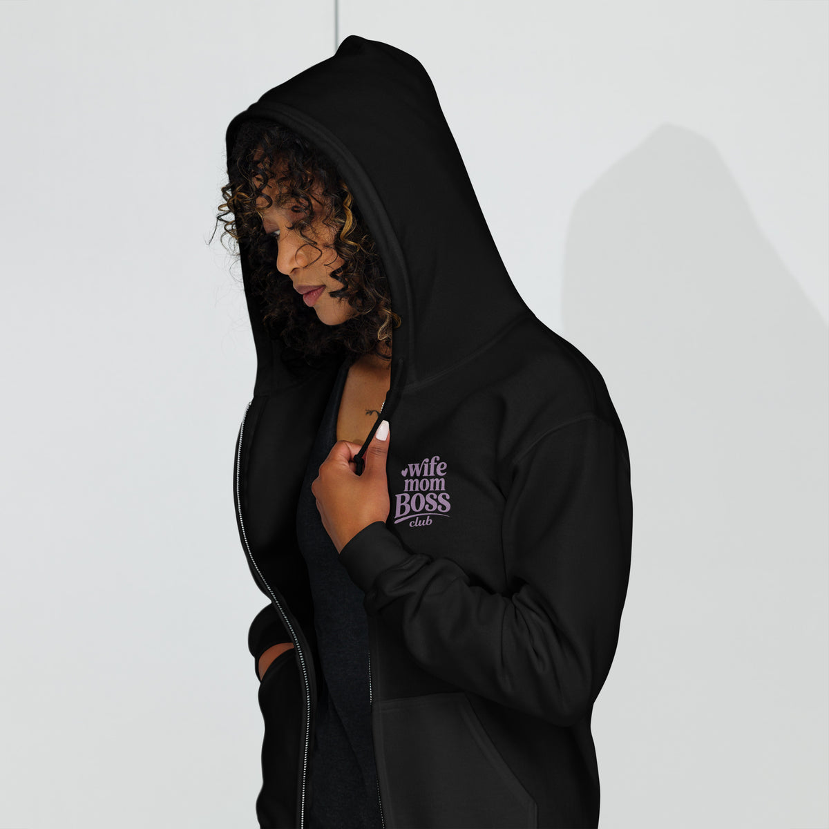Women wearing a black hoodie with 'Wife Mom Boss Club' embroidered  text in lavender on a white background